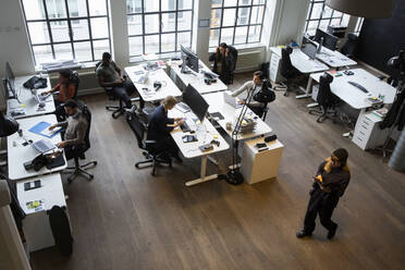 High angle view of male and female professionals working at desk in office - MASF23195