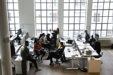 High angle view of male and female professionals discussing during meeting in creative office - MASF23203