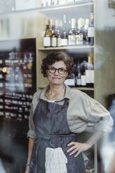 Porträt einer lächelnden Ladenbesitzerin mit Hand auf der Hüfte in einem Feinkostladen - MASF23209