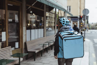 Rückansicht liefert Mann mit Rucksack auf Gehweg - MASF23247