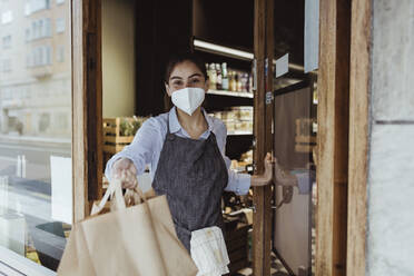 Portrait of female owner with take away food at doorway of delicatessen shop - MASF23262