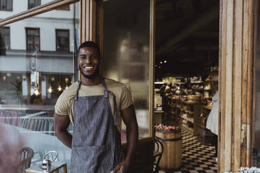 Portrait of smiling male owner standing outside store - MASF23274
