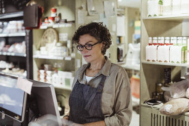 Confident sales woman working on computer in deli store - MASF23298