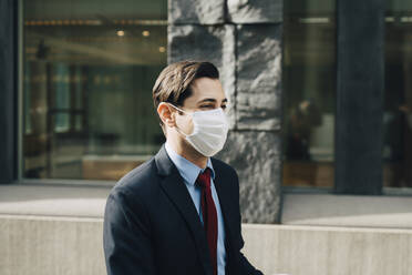 Businessman with protective face mask by office building - MASF23343