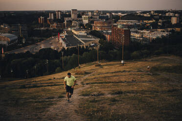 Sportler joggt bei Sonnenuntergang auf dem Land gegen die Stadt - MASF23362