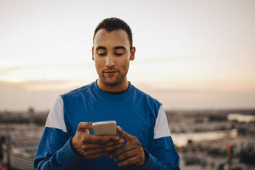 Sportler mit Smartphone gegen den Himmel bei Sonnenuntergang - MASF23371