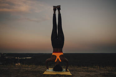 Sportswoman practicing yoga during sunset - MASF23388