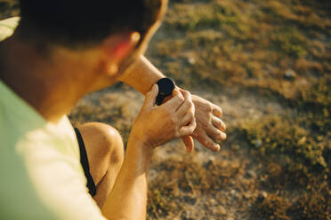 Ausgeschnittenes Bild eines Sportlers, der die Zeit auf seiner Armbanduhr überprüft - MASF23414