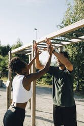 Male and female athlete giving high-five at park - MASF23449