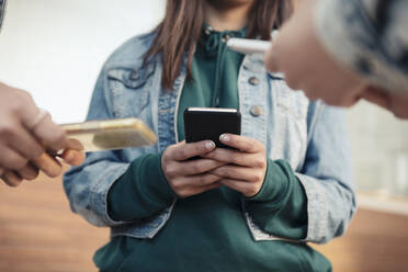 Ausgeschnittenes Bild von Freundinnen, die im Freien ein Smartphone benutzen - MASF23469