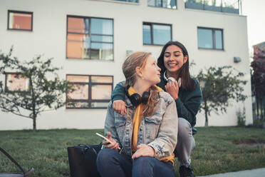 Lächelnde weibliche Teenager im Gespräch miteinander vor einem Gebäude - MASF23484