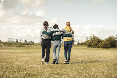Rear view of female friends with arms around walking in park - MASF23500