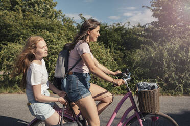 Freundinnen fahren Fahrrad auf der Straße an einem sonnigen Tag - MASF23519