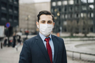 Portrait of businessman with protective face mask in office park - MASF23586