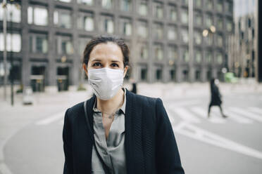 Portrait of female professional with protective face mask in city - MASF23587