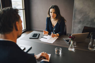 Businesswoman discussing with male colleagues at conference table in office - MASF23651
