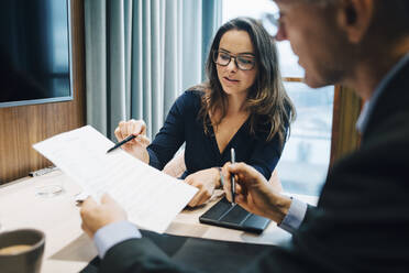 Male and female entrepreneur brainstorming over document during meeting in office - MASF23663