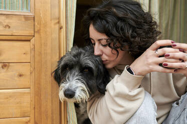 Mittlere erwachsene Frau küsst Hund vor der Tür - KIJF03843