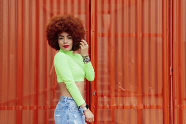 Redhead woman wearing crop top in front standing by red wall - PGF00555