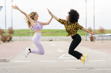 Freundinnen springen auf der Straße im Freien - JCCMF02348