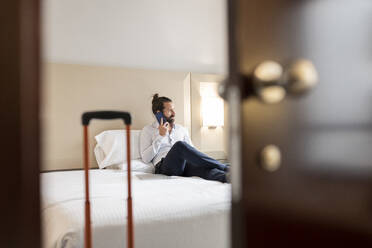 Mann spricht in einer Hotelsuite mit einem Mobiltelefon - JCCMF02416