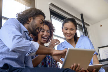 Internationale Studentinnen und Studenten lächeln bei der Nutzung eines digitalen Tablets in der Universität - BMOF00587