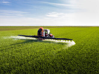 Landwirt beim Düngen der Pflanzen mit der Feldspritze auf dem Feld - NOF00182