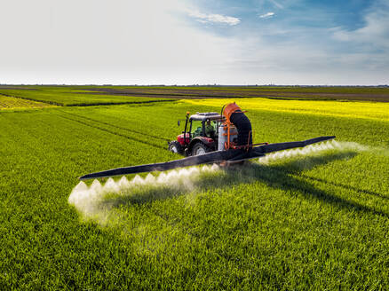 Traktor beim Sprühen von Pestiziden auf einem Weizenfeld an einem sonnigen Tag - NOF00183