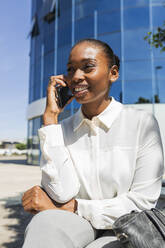 Mid adult businesswoman talking on mobile phone during sunny day - JRVF00571