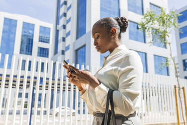 Female entrepreneur using mobile phone in city - JRVF00572