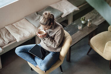 Mid adult businesswoman drinking coffee while sitting at cafe - JOSEF04366