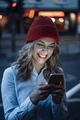 Beautiful woman smiling while using mobile phone - JOSEF04368