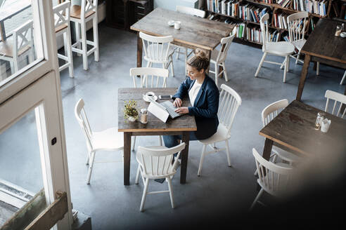 Female entrepreneur working on laptop in coffee shop - JOSEF04379