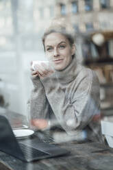 Female entrepreneur with coffee cup contemplating at coffee shop - JOSEF04385