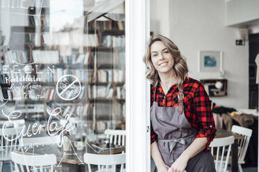 Female owner leaning on door at cafe - JOSEF04389