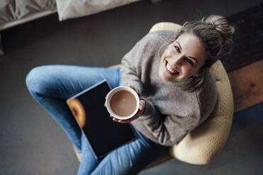 Glückliche Besitzerin hält eine Cappuccino-Schale, während sie in einem Café sitzt - JOSEF04404