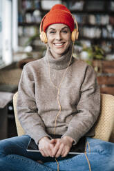 Businesswoman with headphones and digital tablet sitting in coffee shop - JOSEF04406