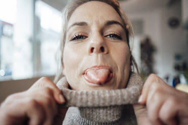 Mid adult woman sticking out tongue in cafe - JOSEF04413