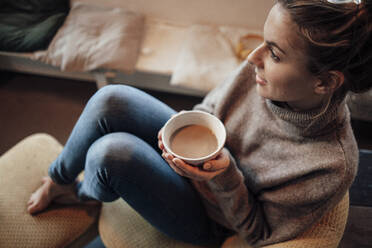 Thoughtful woman holding coffee bowl while sitting in cafe - JOSEF04418