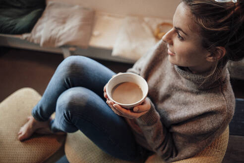 Nachdenkliche Frau hält eine Kaffeeschale, während sie in einem Café sitzt - JOSEF04418
