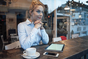 Mid adult female owner looking through window in coffee shop - JOSEF04420