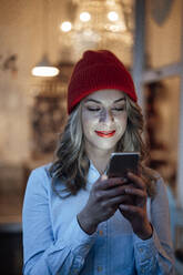 Mid adult businesswoman wearing knit hat using mobile phone - JOSEF04424