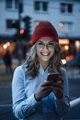 Geschäftsfrau lächelnd bei der Verwendung eines Smartphones bei Sonnenuntergang - JOSEF04425