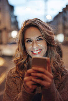 Mittlere erwachsene Frau lächelt und hält ein Smartphone - JOSEF04428