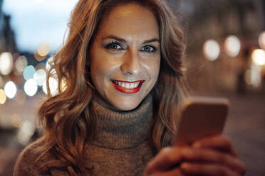 Lächelnde blonde Frau hält Smartphone - JOSEF04430