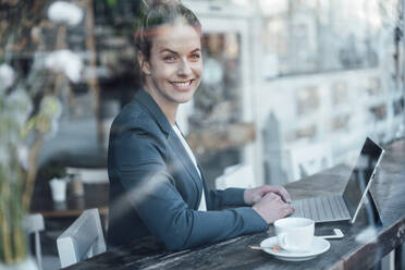 Businesswoman with digital tablet looking through cafe window - JOSEF04465