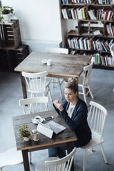 Mittlere erwachsene Geschäftsfrau mit digitalem Tablet in einem Café sitzend - JOSEF04468