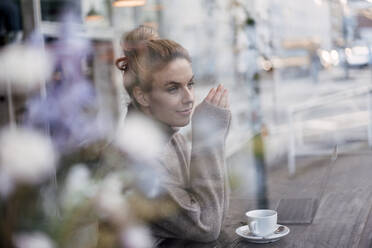 Thoughtful female customer looking away at coffee shop - JOSEF04477