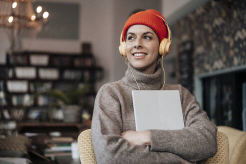 Mittlere erwachsene Frau mit digitalem Tablet, die in einem Café über Kopfhörer Musik hört - JOSEF04484