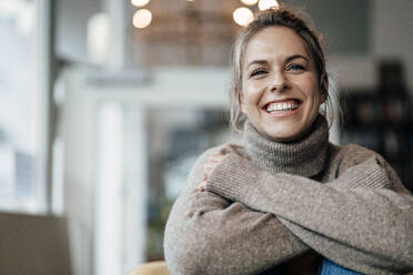 Mid adult woman wearing sweater smiling at cafe - JOSEF04486